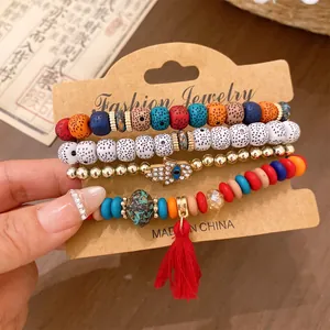 Detail view of bohemian beaded bracelet set featuring Hamsa hand charm and red tassel