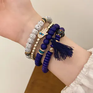 Detail of Bohemian multilayer beaded bracelet set featuring blue tassel and Hamsa Hand charm