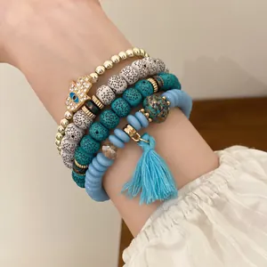Close-up of bohemian beaded bracelet set featuring a Hamsa hand charm and blue tassel.