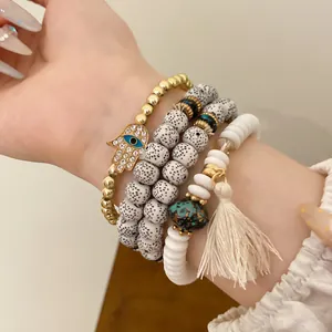 Close-up detail of ethnic beaded bracelet set with Hamsa hand charm and cream tassel charm