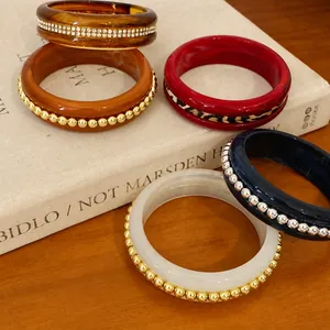 Elegant resin bangles set with rhinestone and gold bead accents on a vintage book