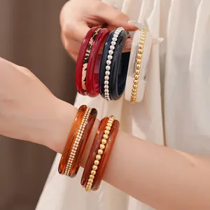 Detailed macro view of stackable resin bangles with rhinestones and gold beads worn on wrist