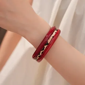 Detail shot of a three-piece resin bracelet set with red and leopard print bangles.