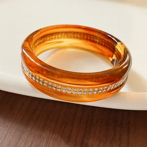 Detailed close-up of amber resin bangle featuring shimmering inlaid rhinestone band