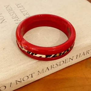 Close-up of a red resin bangle featuring a stylish leopard print inlay detail