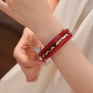 Detailed shot of a stylish red resin and leopard print bangle bracelet set on a wrist