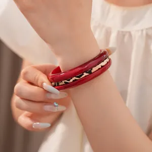 Close-up of elegant red resin bangles and leopard print bracelet on wrist