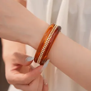 Close-up of an amber resin bangle bracelet with double rows of sparkling rhinestones.