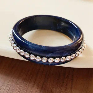Macro detail showing a minimalist navy blue resin bangle with embedded silver beads