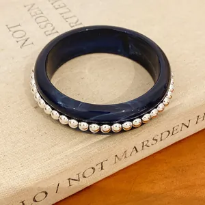 Detail view of a navy blue resin bangle with elegant silver bead trim on a book.