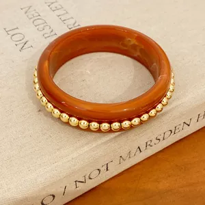 Close-up detail of minimalist brown resin bangle accented with elegant gold bead trim