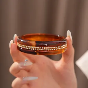 Close-up view of an elegant amber resin bangle with double-row rhinestone inlay details