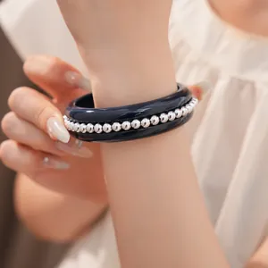 Detail view of a navy blue resin bangle bracelet featuring silver metallic beads on wrist
