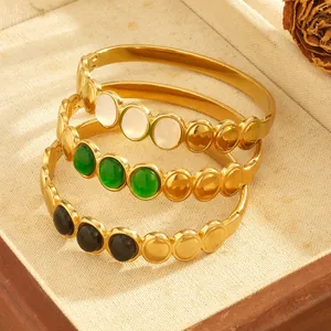 Stacked gold-plated stainless steel bangles with round black, green, and white stone insets.