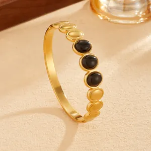 Macro view of bohemian gold PVD plated stainless steel bangle with black oval stones