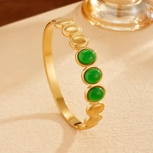 Close-up of bohemian gold PVD plated stainless steel bangle with green stone inlays