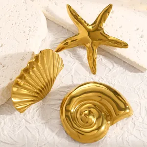 Detalle de cerca de broches de acero inoxidable dorado con forma de estrella de mar y concha