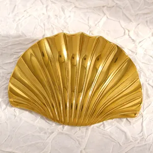 Detalle de un broche de acero inoxidable dorado con forma de concha sobre fondo blanco