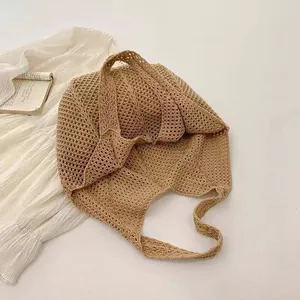 Macro view of the hollow-out crochet pattern on this bohemian beige knitted tote bag.