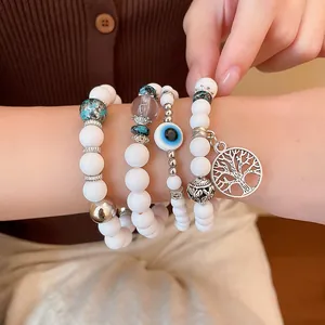 Detail view of Bohemian white beaded bracelet set with Tree of Life and Evil Eye charms