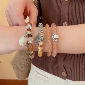 Close-up of Bohemian beaded bracelet set with shell and leaf charms on wrist