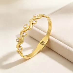 Goldener Armreif mit Herzsteinen, gedrehtem Design und Federverschluss in der Detailansicht