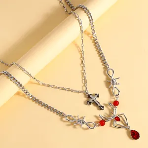 Close-up van een dubbellaagse punkketting met kruis- en rode spinnengem-hangers sieraden