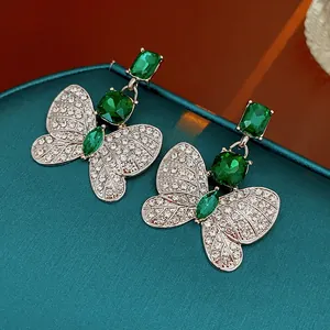 Nahaufnahme eleganter smaragdgrüner Schmetterlingsohrringe mit funkelnden Flügeln.