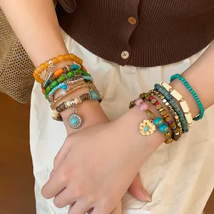 Detail view of colorful bohemian multi-layered beaded bracelets with turquoise charms.