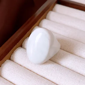 Makroaufnahme eines glatten weißen Harzrings in einer cremefarbenen Schmuckschatulle aus Samt