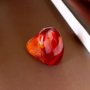 Makroaufnahme eines künstlerischen Rings aus rotem und orangefarbenem Harz mit Glanz