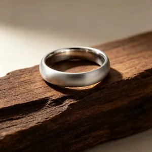 Macro view of a minimalist brushed stainless steel ring on a textured wood surface background