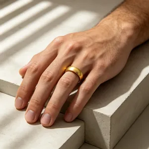 Detailed view of a matte gold-finished stainless steel dome ring worn on a male hand