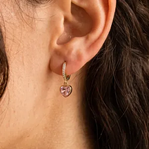 Gros plan détaillé d'élégantes créoles dorées avec pendentif étincelant en zircon rose cœur