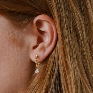 Vue détaillée d'une boucle d'oreille créole en acier doré avec pendentif en zircon