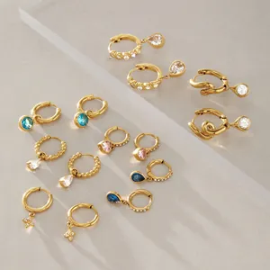 Vue détaillée de plusieurs boucles d'oreilles créoles dorées en acier titane et zircon.