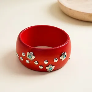 Close-up of a red vintage wood-style bangle with silver flower and rivet studs