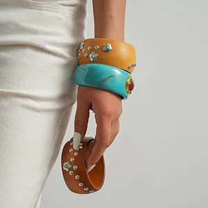 Detailed macro view of vintage resin and wooden bangles featuring flower rivet studs