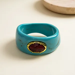 Detail shot of a retro marbled turquoise resin bangle with a red faux gemstone