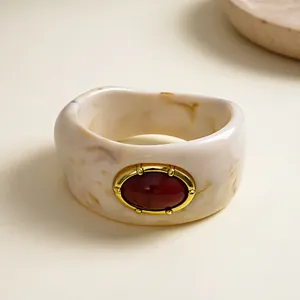Detail of a vintage marbled resin chunky bangle featuring a central oval red stone inlay