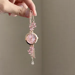 Close-up detail of elegant rose gold bracelet watch with pink floral crystal accents
