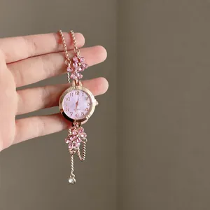 Detail of rose gold bracelet watch with pink crystal flower accents held in hand.