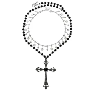 Gros plan d'un pendentif croix gothique sur un collier à plusieurs rangs de perles noires