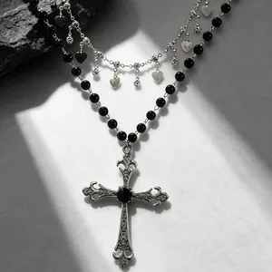 Vue détaillée d'un collier gothique punk avec pendentif croix, perles noires et cœurs.