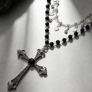 Gros plan détaillé du collier pendentif croix gothique vintage avec perles noires et cœurs