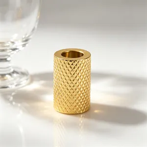 Macro detail of a golden cylinder spacer bead with knurled diamond pattern texture.