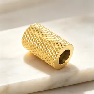 Detailed close-up of a golden cylindrical spacer bead featuring a diamond-cut grid texture