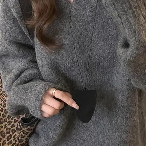 Vue détaillée d'un collier porte-lunettes magnétique en cuir noir de forme triangulaire.