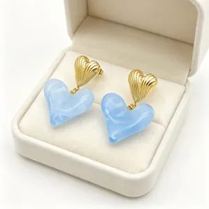 Vue rapprochée de boucles d'oreilles cœur bleu clair avec haut doré texturé en boîte cadeau