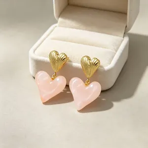Détail macro de boucles d'oreilles cœur avec métal doré nervuré et résine marbrée